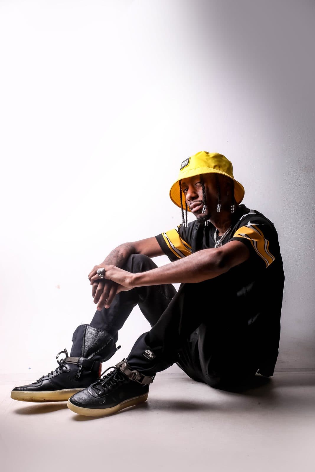 Ojizzy sentado no chão do estúdio com bucket hat amarelo